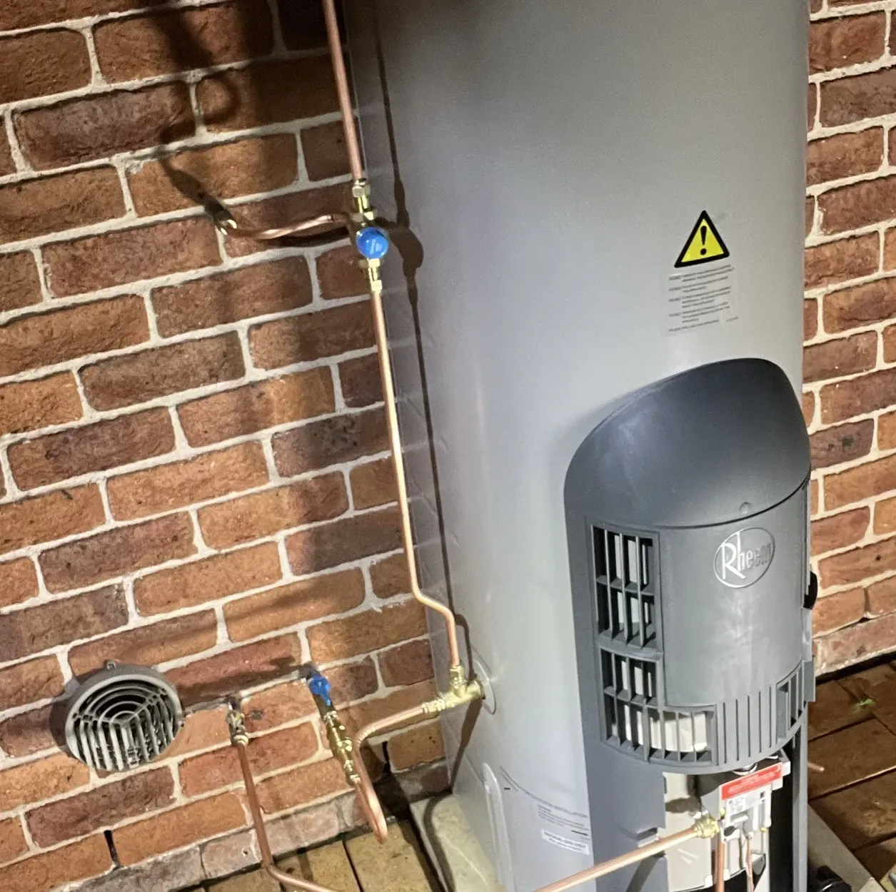 New Rheem gas storage hot water unit with new copper pipes and valves against a brick wall in Castle Hill