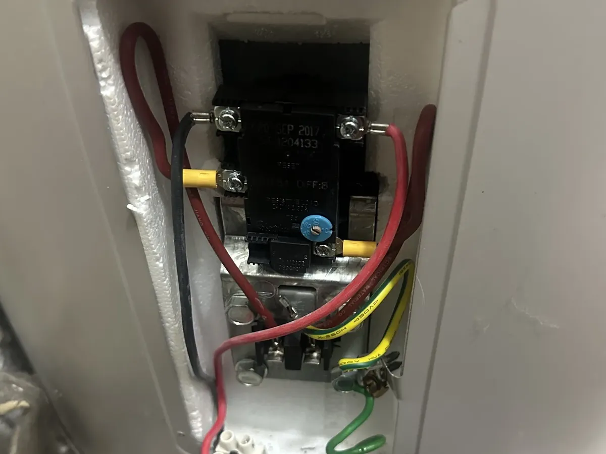 Thermostat and wiring exposed behind the element cover of an electric tank in Bankstown