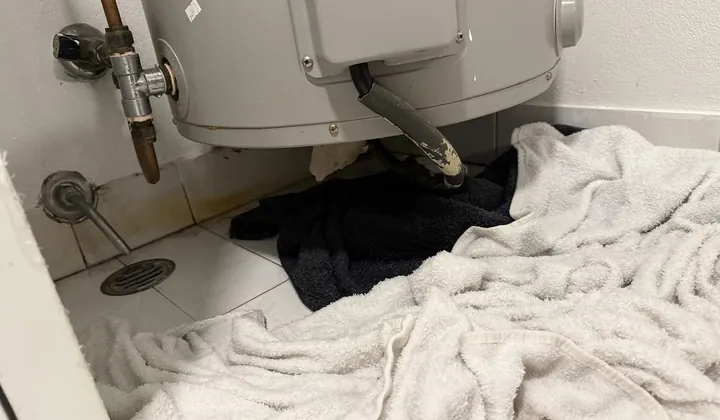 Towels on a laundry floor soaking up water leaking from under a hot water tank