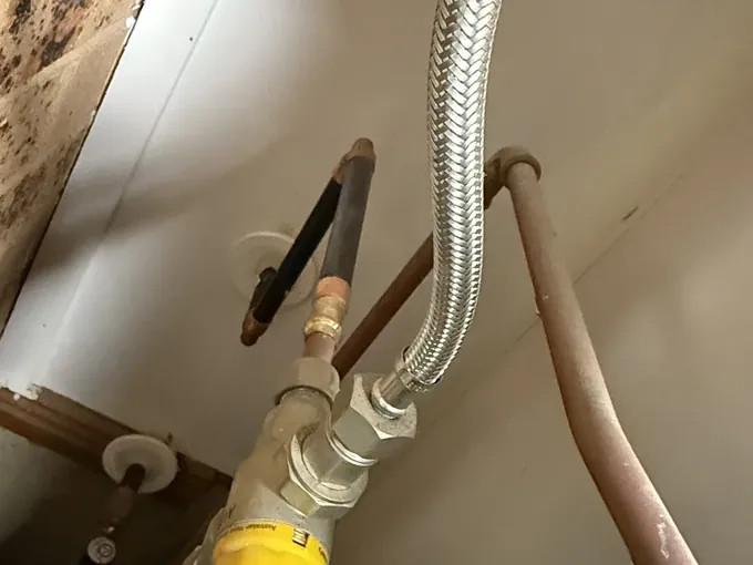 Braided hose and isolation valve connected under a hot water tank