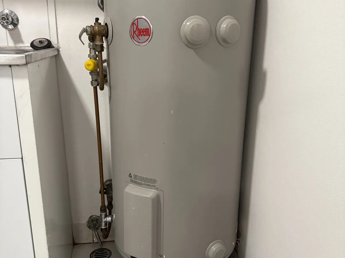 Rheem electric hot water tank in a laundry with towels on the floor around its base