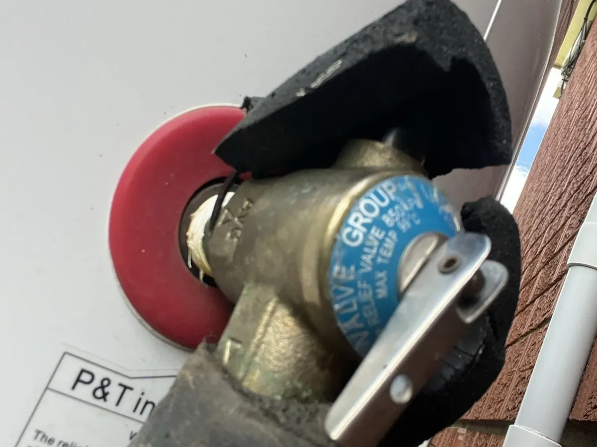 Temperature and pressure relief valve on a hot water tank with lagging around the pipe