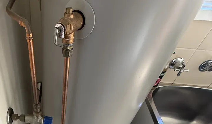 Relief valve with its lever and copper drain pipe on an indoor gas storage hot water tank in Tempe