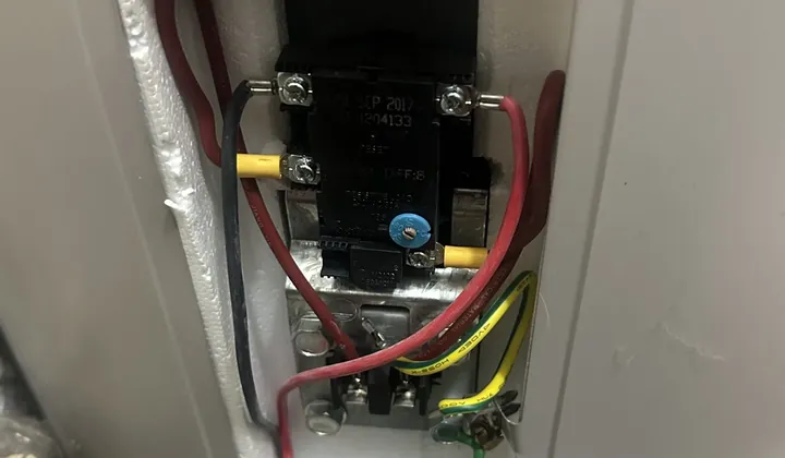 Thermostat and wiring exposed behind the element cover of an electric tank in Bankstown