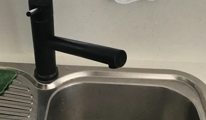 Black kitchen mixer tap over a stainless steel sink in Mount Druitt