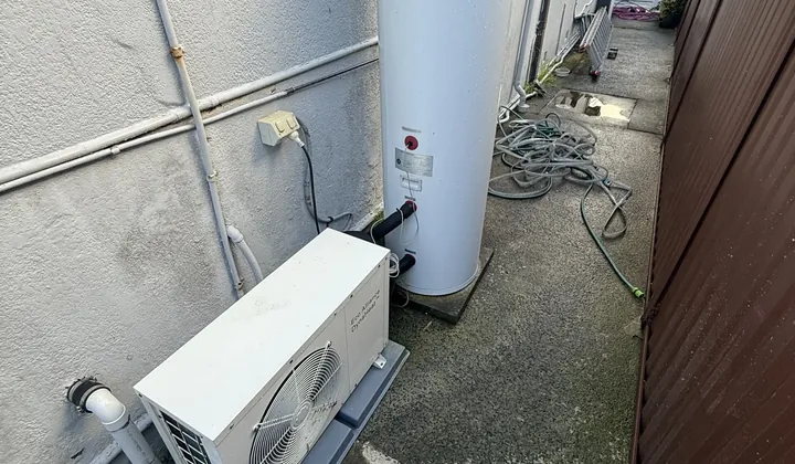 Heat pump hot water system with its outdoor unit beside a house