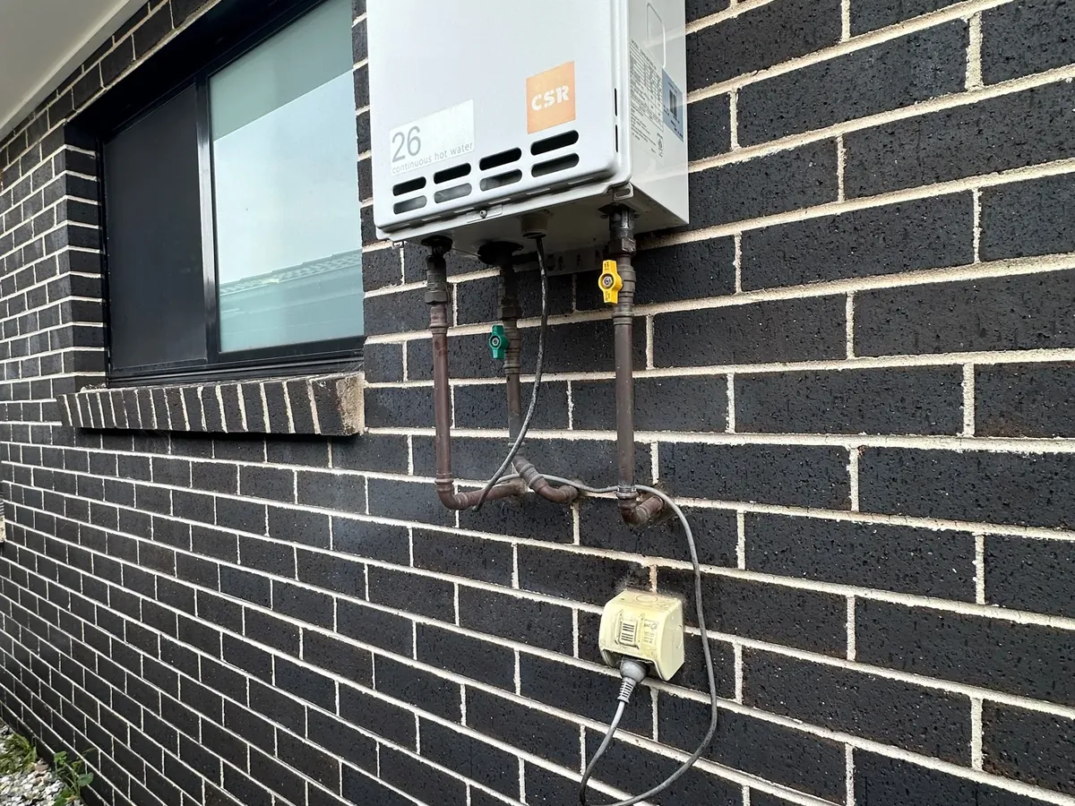 Bradford continuous flow gas hot water unit on an outside wall beside a window