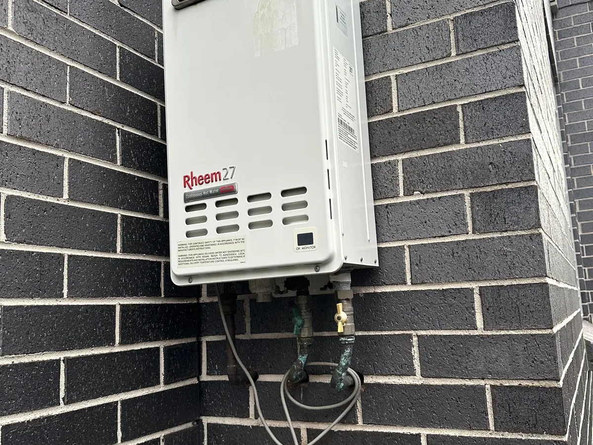 Rheem 27 continuous flow gas hot water unit on an outside brick wall
