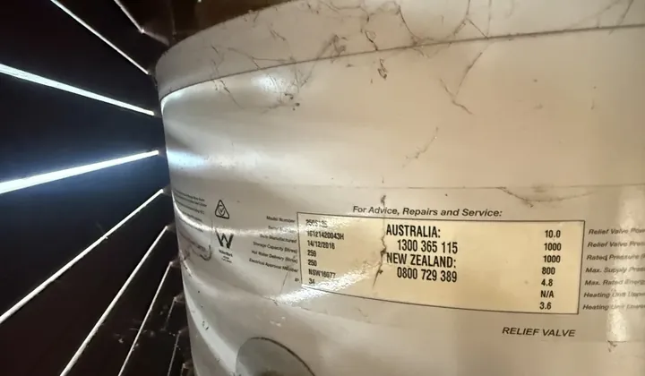 Data plate on an electric hot water tank in a cupboard showing 250 litres