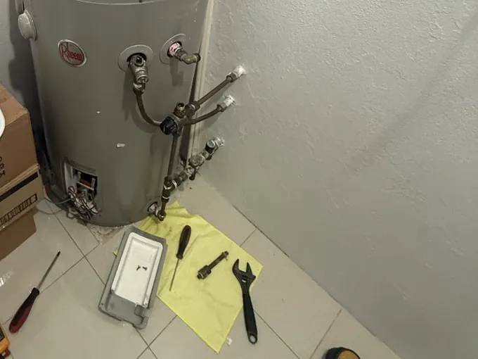 Rheem electric tank with the element cover off and hand tools on a cloth beside it in Bankstown