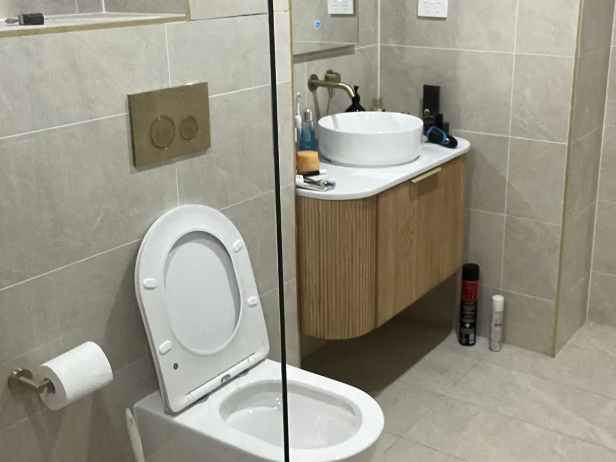 In-wall cistern flush plate above a wall-faced toilet in Strathfield