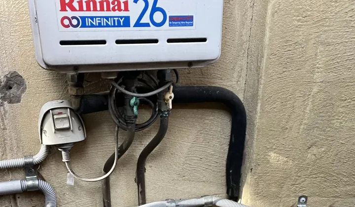 Rinnai continuous flow unit with its gas line and an insulated hot water pipe on a rendered wall in Hunters Hill