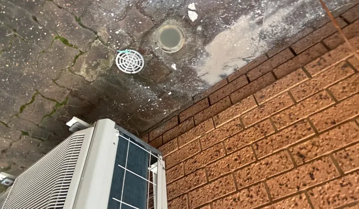 Kitchen drain gully with its grate lifted and grey residue across the pavers in Bossley Park