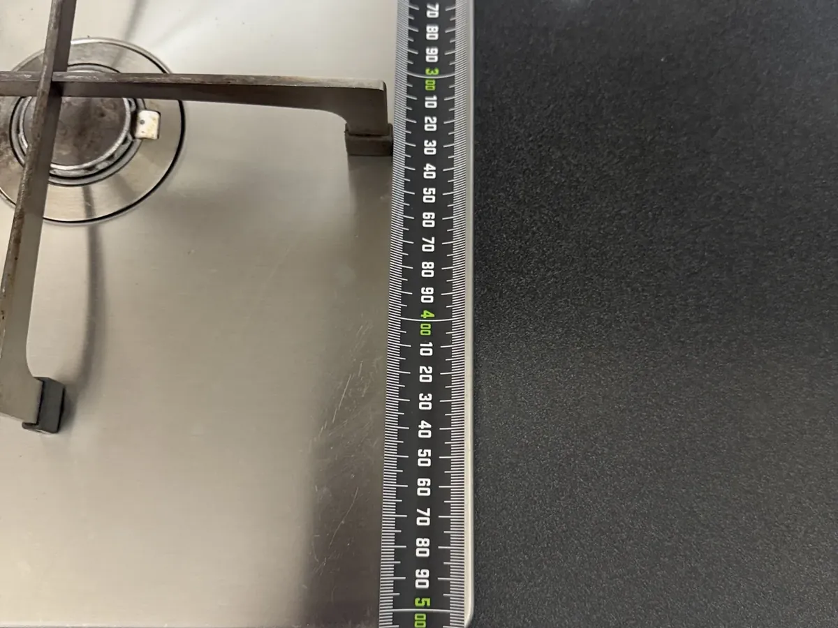 Tape measure across a stainless gas cooktop, measuring the bench cut-out in Bankstown