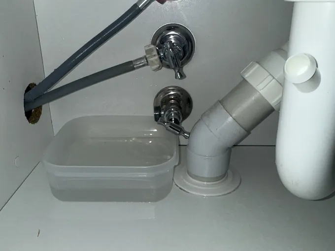 Washing machine taps and a waste pipe inside a laundry cabinet