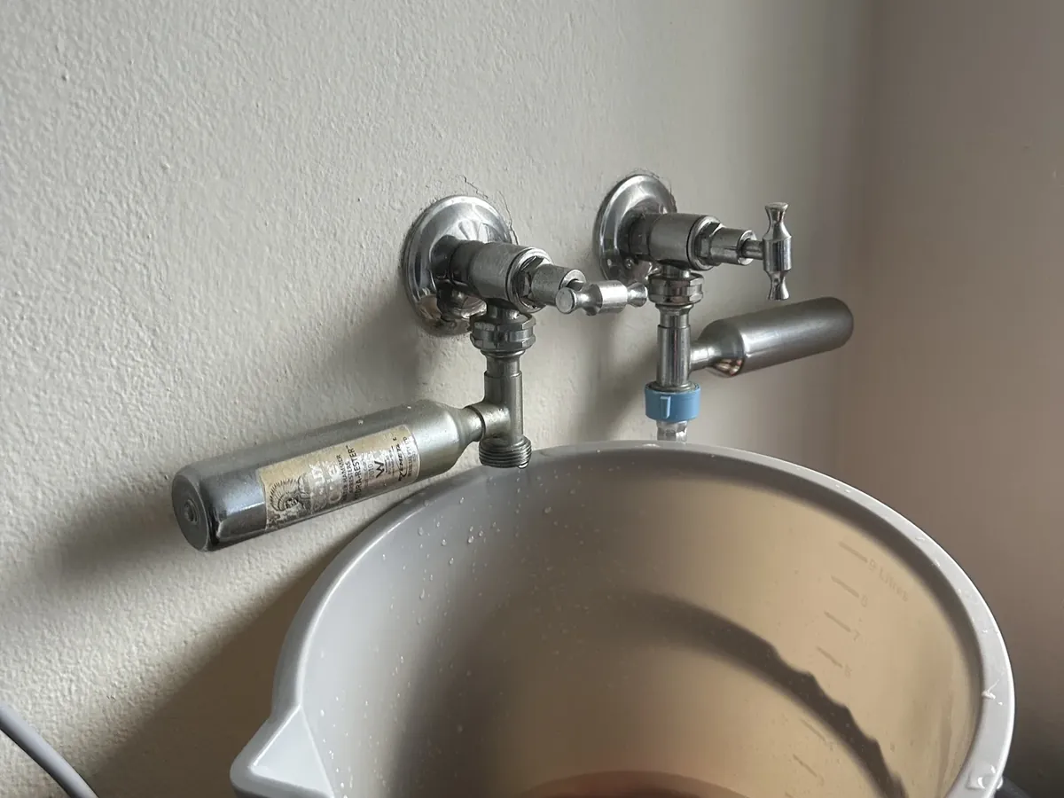 Old laundry taps with water hammer arrestors dripping into a bucket
