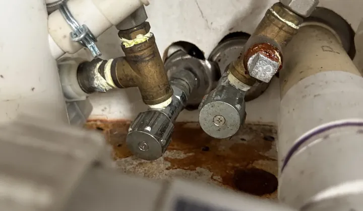 Rust-stained isolation valves and pipes under a sink in Edgecliff