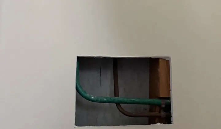 Access hole cut in a wall to reach copper water pipes in Roselands