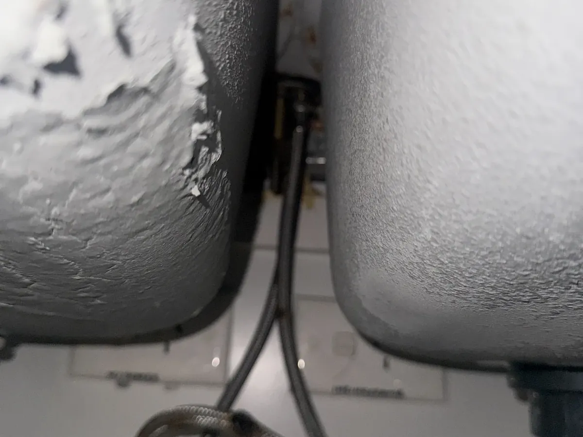 Braided water hoses under a kitchen sink in Haberfield