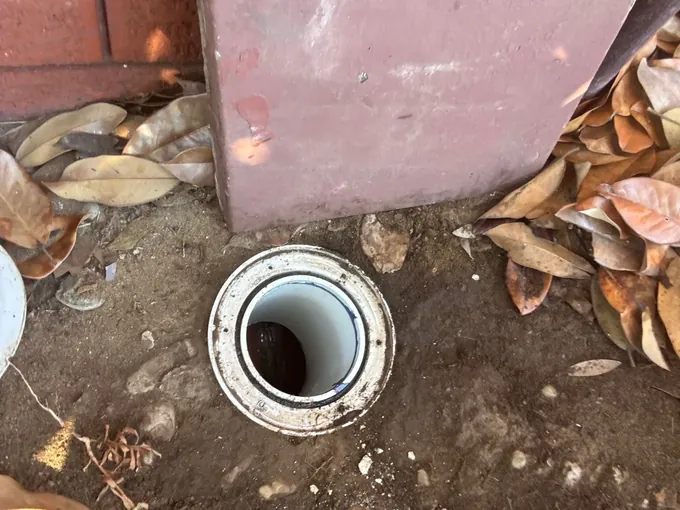 Inspection opening uncovered in the soil beside a lifted paver in Beverly Hills