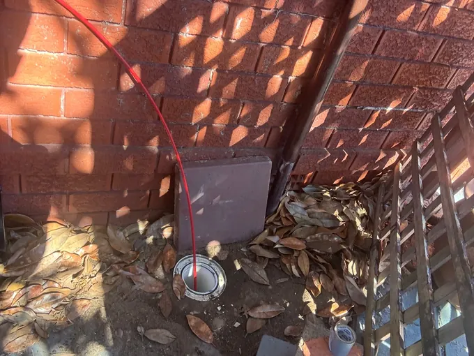 Jet blaster hose fed into an inspection opening in the corner of a yard in Beverly Hills