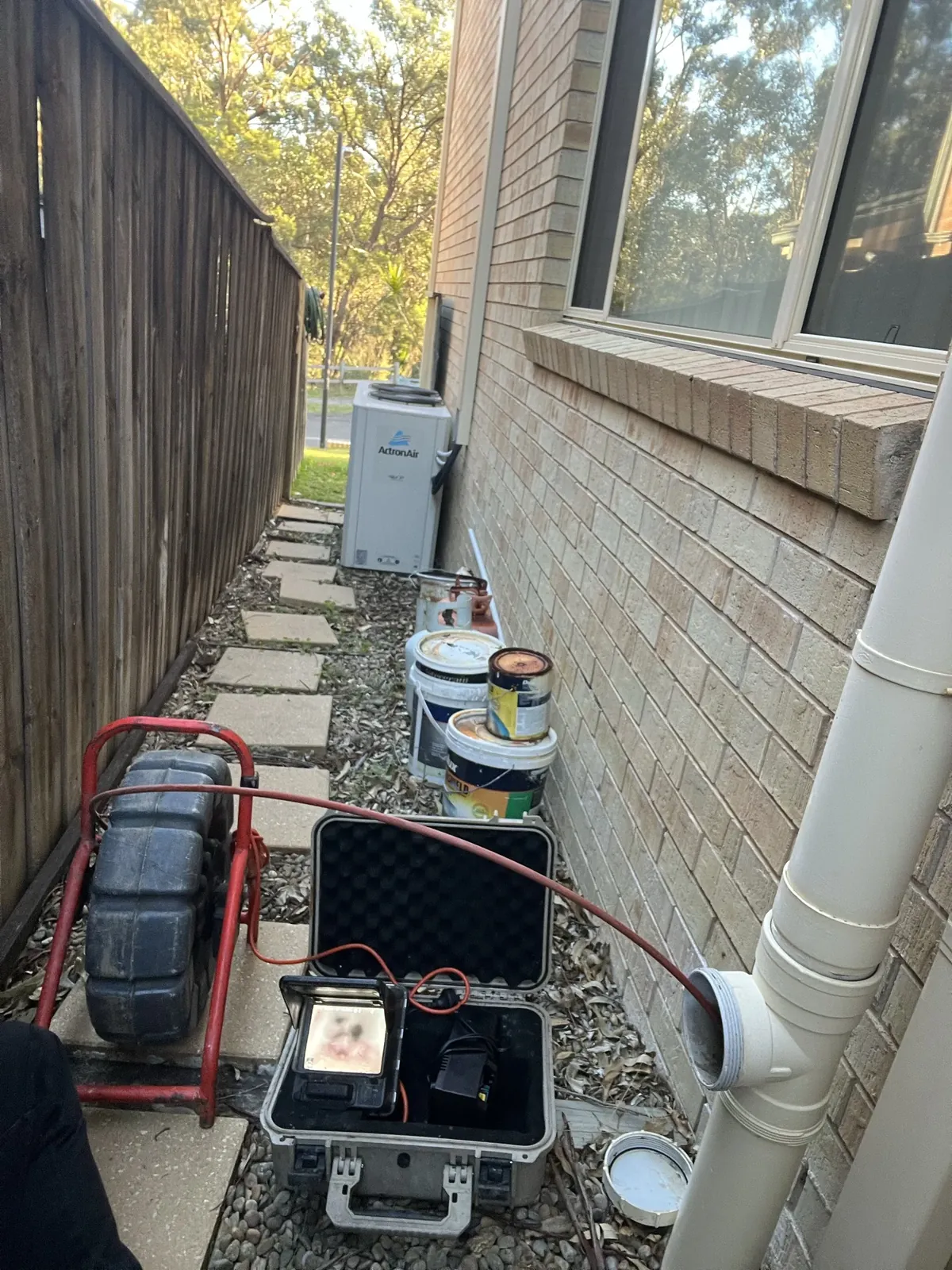 Drain camera reel and monitor set up at a sewer access point beside a house