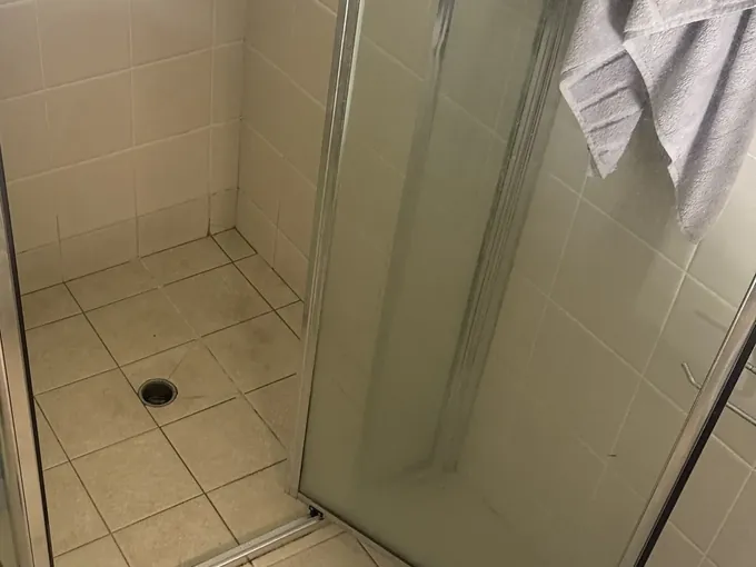 Shower recess and floor waste in an upstairs bathroom with a towel over the screen in Granville