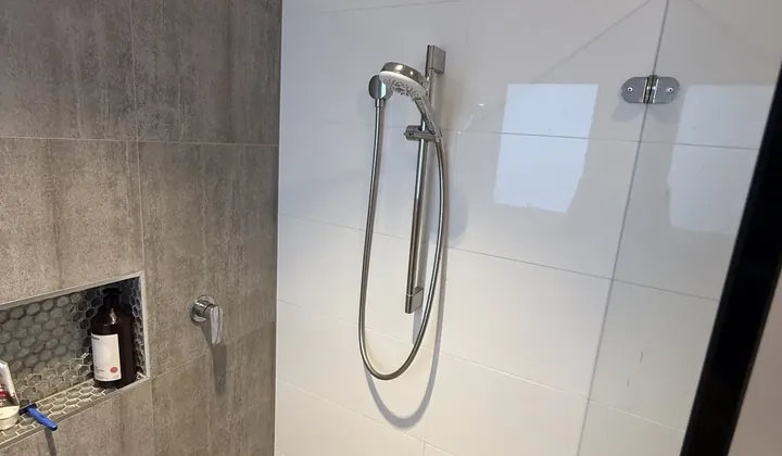 Hand shower on a rail in a tiled bathroom in North Willoughby