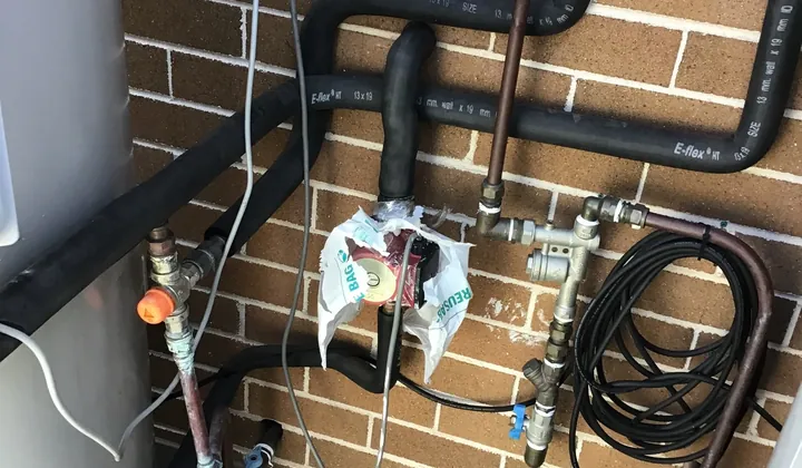 Brass valves and pipework on the water supply beside a hot water system in Enfield