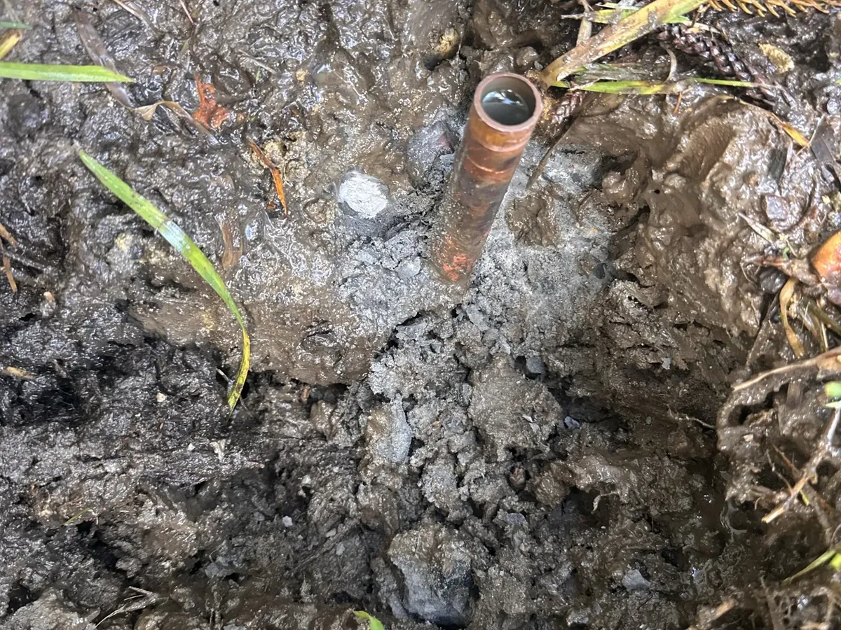 Copper water pipe uncovered in wet ground near the water meter in Riverwood