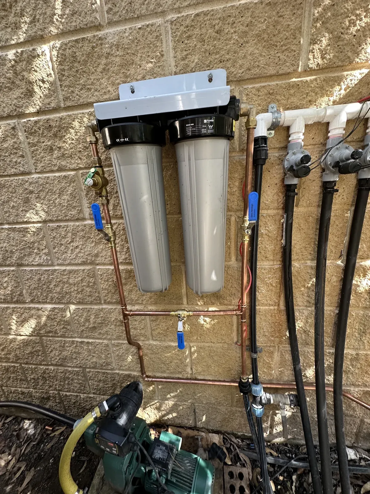 Twin filter housings with isolation valves and a bypass, fitted beside the pump on a tank water supply in Wilberforce