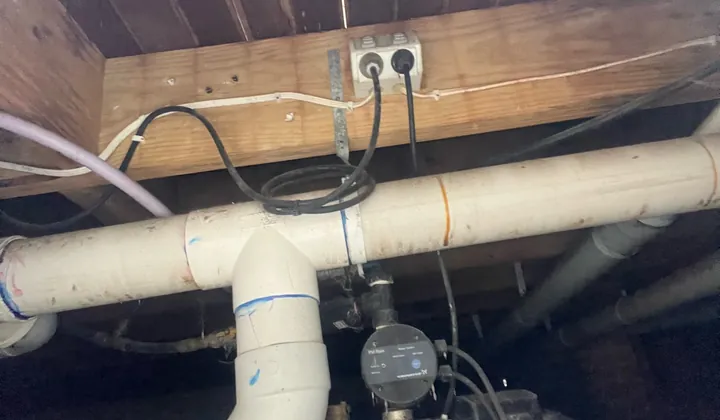 Rainwater pump and its controller mounted under a house beside PVC pipes in Beverly Hills