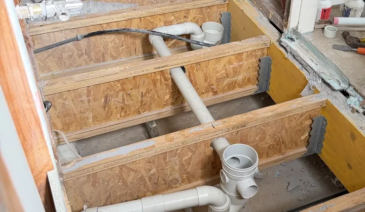 New PVC drainage run through the floor joists of a bathroom under renovation in Padstow