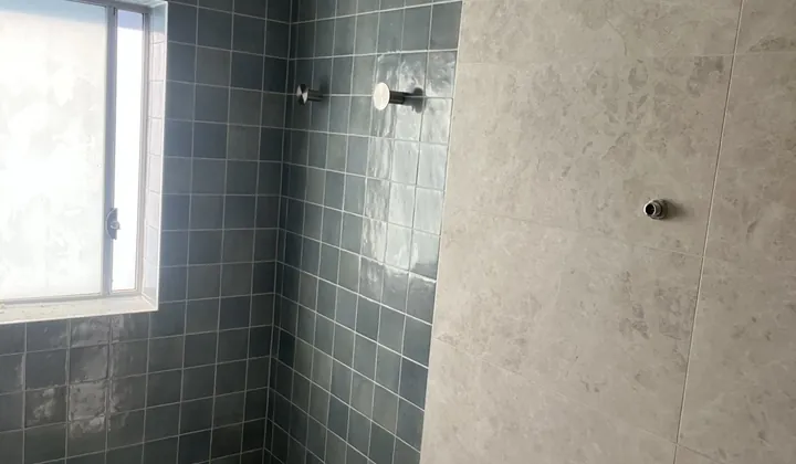 Freshly tiled bath alcove with blue wall tiles and stone-look floor tiles before the fittings go in, Padstow
