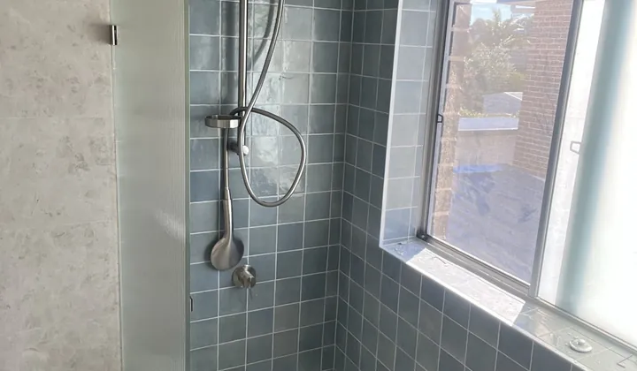 New bath with a shower over it, blue wall tiles and a fixed glass screen in a Padstow renovation