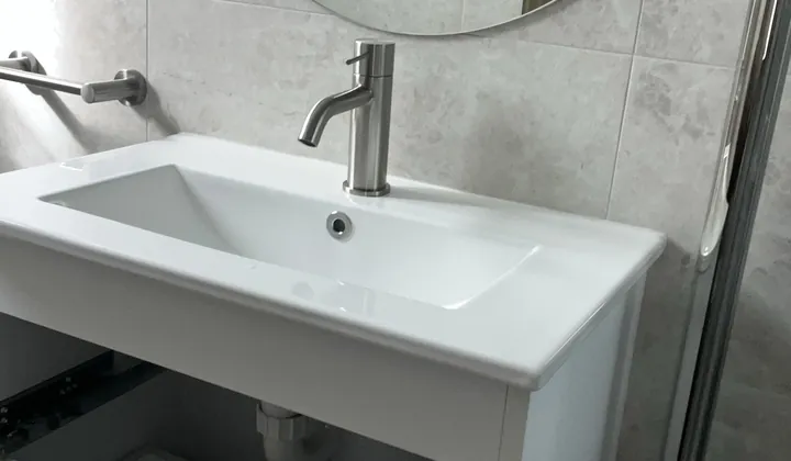 New wall-hung vanity with a basin mixer and round mirror in a Padstow bathroom