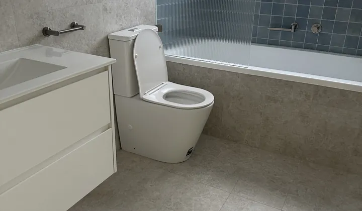 Completed bathroom renovation in Padstow with a white vanity, back-to-wall toilet and blue feature tiles