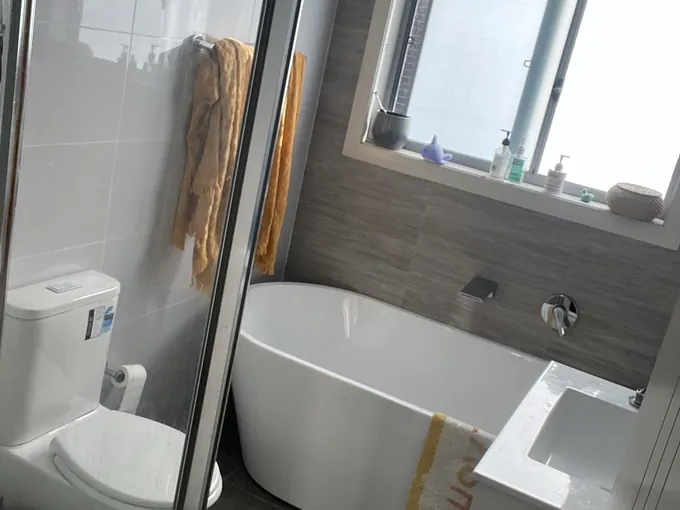 Original bathroom in Padstow before renovation, with a freestanding bath and a shower screen