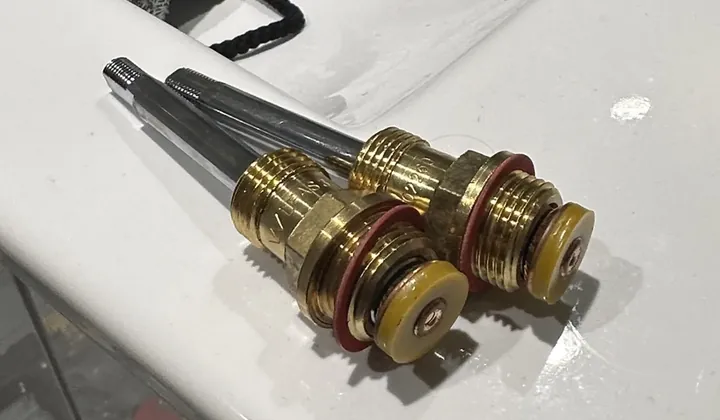 Two worn brass tap spindles taken out and laid on the edge of a vanity in Surry Hills
