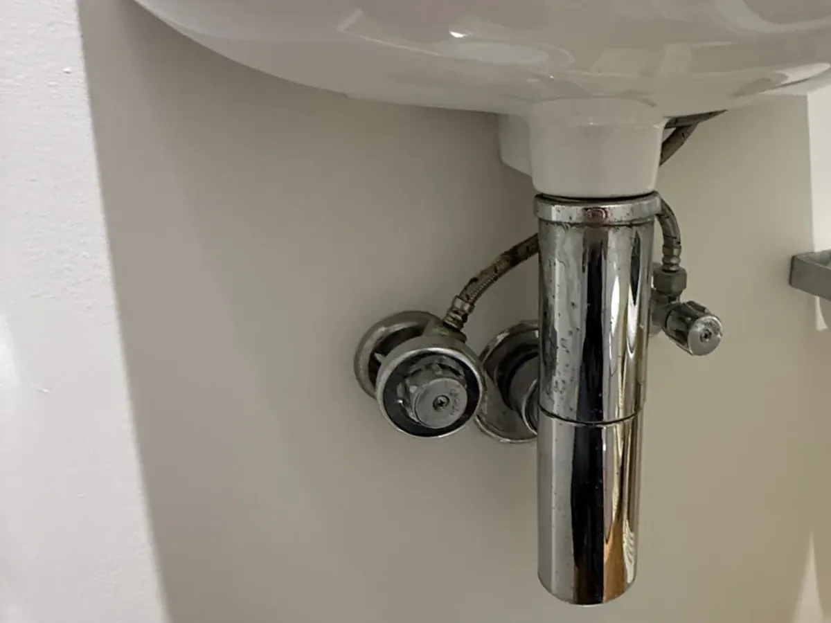 Wall-hung basin with a chrome bottle trap and two stop taps underneath in Newtown