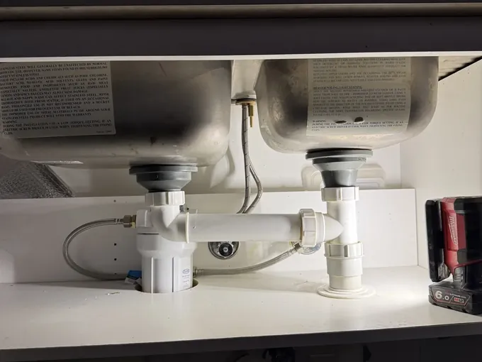 Kitchen tap running above a new under-sink water filter and the sink wastes in Edmondson Park
