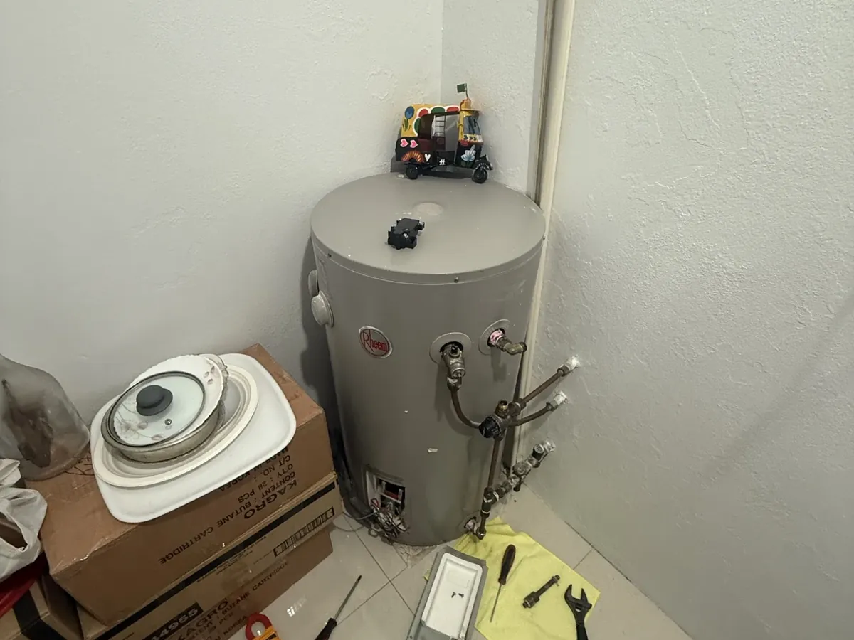 Rheem electric tank with the element cover off and hand tools on a cloth beside it in Bankstown
