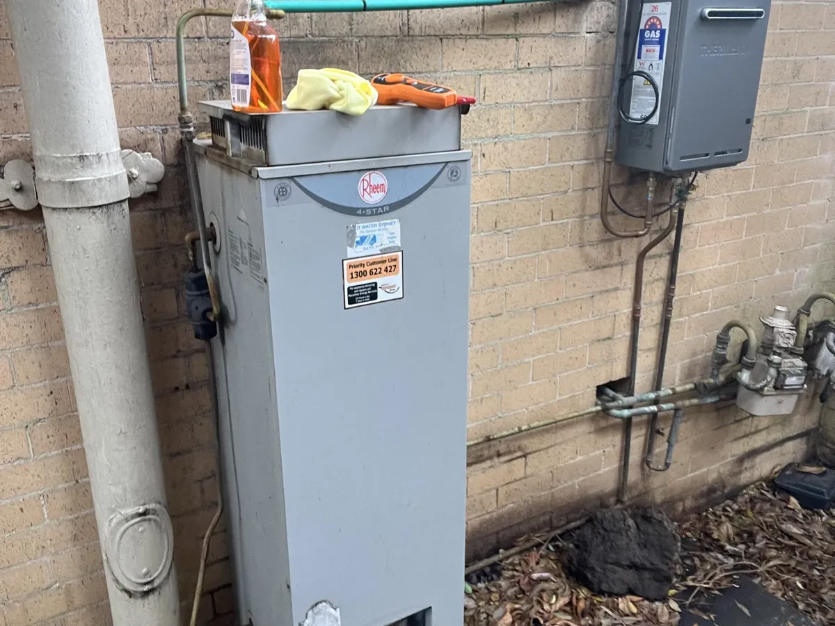 Older Rheem 4 star gas storage hot water system outside a brick wall