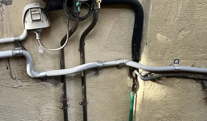 Rinnai continuous flow unit with its gas line and an insulated hot water pipe on a rendered wall in Hunters Hill