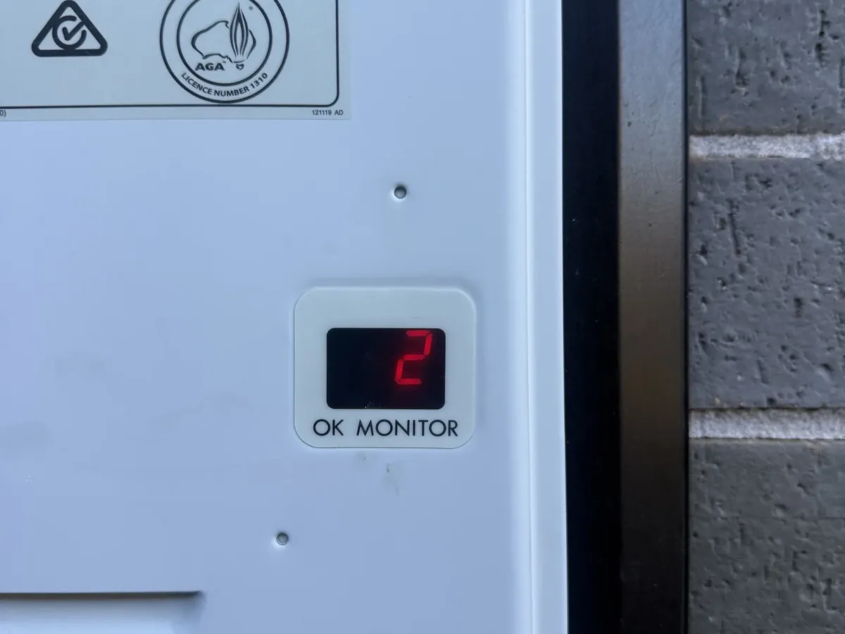 Red number on the monitor display of a continuous flow gas unit beside a brick wall in Denham Court