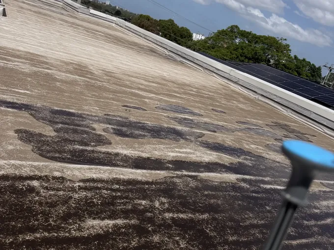 Pump sprayer on the edge of a flat roof with wet patches during a leak check in Northmead