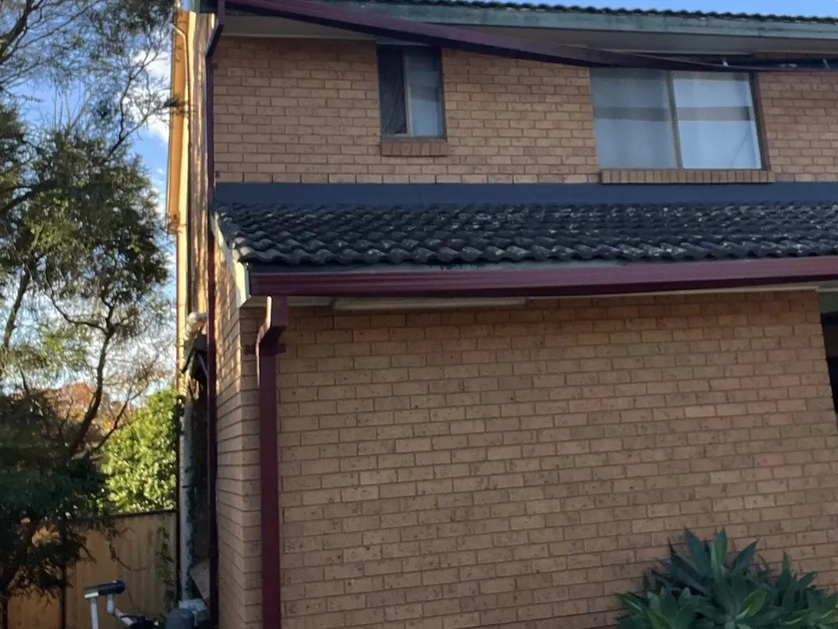 Roof lines, gutters and a downpipe on the back of a two-storey brick home in Wakeley