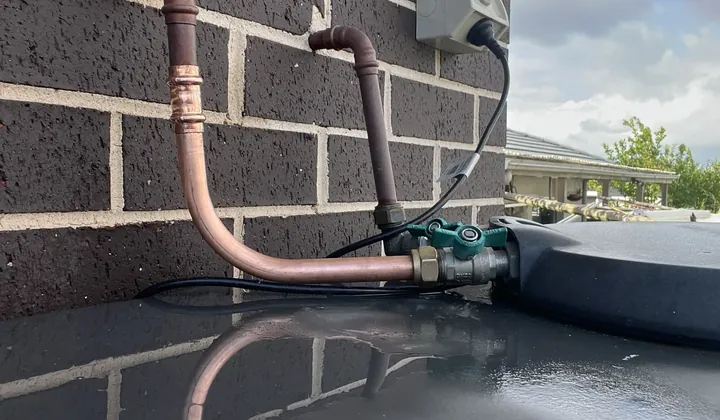 Section of copper water pipe repaired with new pressed fittings beside a brick wall