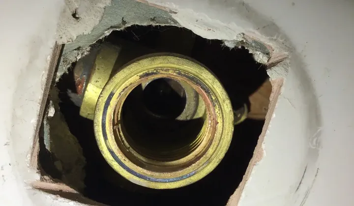 Wall opened behind a tap to expose the brass fitting inside