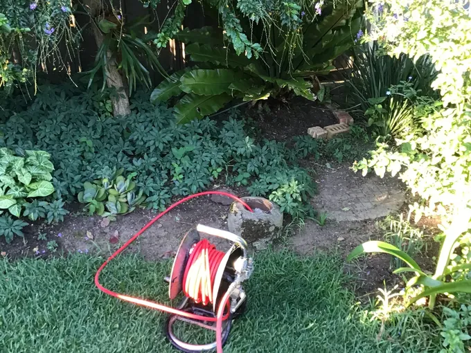 Hose reel from the jet blaster run into a garden drain riser in Casula